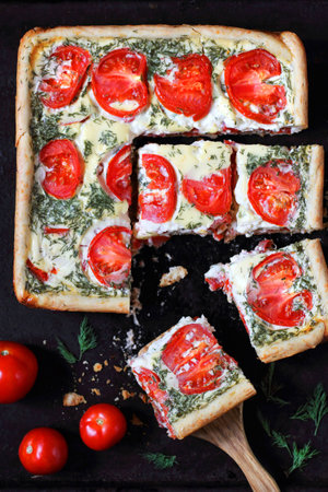 sliced cake with tomatoes, cheese and dill on a black backgroundの写真素材