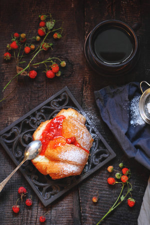 bun with homemade strawberry jam and coffee on a wooden backgroundの写真素材