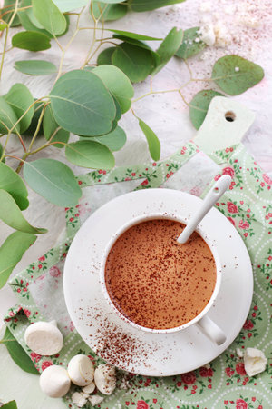 coffee sprinkled with cocoa powder in a white cup on a green napkinの写真素材