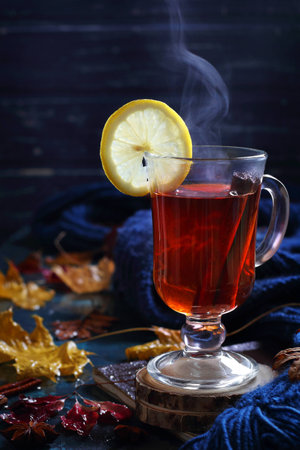 cup of hot black tea with cinnamon and lemon in autumn decorations, natural smokeの写真素材