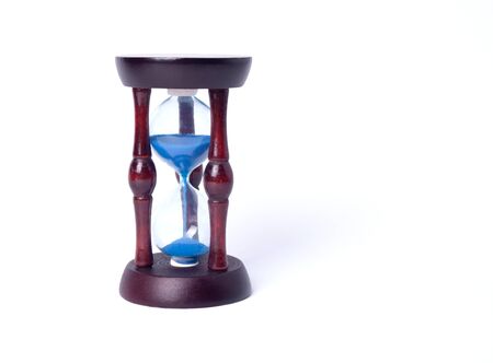 Close-up of hourglass with blue sand in a rustic vintage frame on a white background isolating