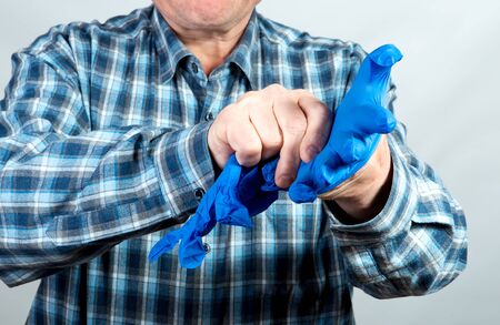 Man puts on a glove to protect his hands from the virus during a pandemicの写真素材