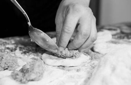 How not to get bored at home during quarantine and isolation? Hobbies for cooking belyashes according to the Ukrainian recipe. Step 4. Using a tablespoon, put a portion of minced meat on a piece of rolled dough under one belyash.の写真素材