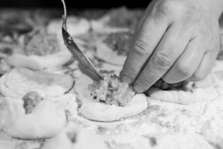 How not to get bored at home during quarantine and isolation? Hobbies for cooking belyashes according to the Ukrainian recipe. Step 4. Using a tablespoon, put a portion of minced meat on a piece of rolled dough under one belyash.の写真素材