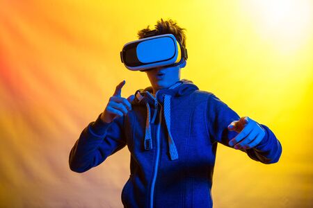 Emotions and joy of a young man using virtual reality. Photo of a young man in blue tones on the...