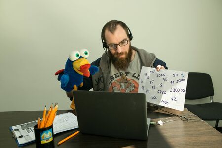 Online lesson. A young man conducts an online lesson during quarantine. As a visual aid, he uses a toy.の写真素材