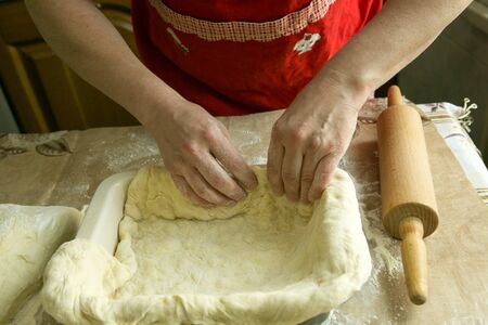 Mom's pies. Mom's hands put the dough into the mold. Cooking during quarantine.
