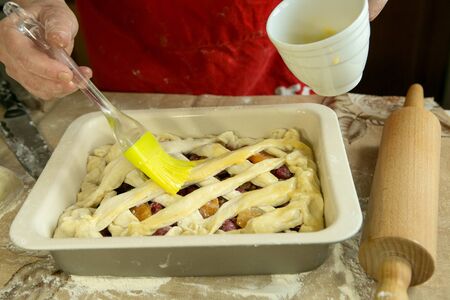 Mom's pies. Mom lubricates the cake before baking with a cooking brush. Mom's hands. Cooking during quarantineの写真素材
