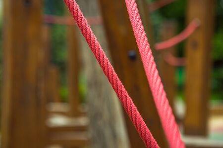Red hemp cable on a background of wooden boards. Fragments of the construction of wooden bars in the playground. Computer desktop wallpaper.の写真素材