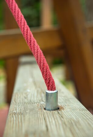 Red hemp cable on a background of wooden boards. Fragments of the construction of wooden bars in the playground. Computer desktop wallpaper.の写真素材