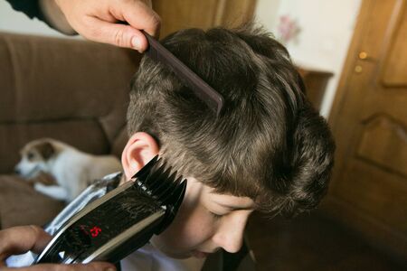 Home haircut during quarantine. The best master is mother's hands, scissors and a trimmer.の写真素材