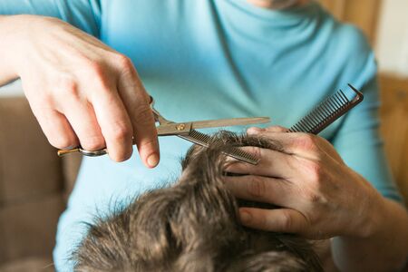 Home haircut during quarantine. The best master is mother's hands, scissors and a trimmer.の写真素材