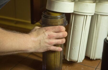 The master replaces dirty filters in the home water purification system. Human hands, filter, membrane.の写真素材