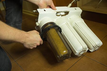 The master replaces dirty filters in the home water purification system. Human hands, filter, membrane.の写真素材