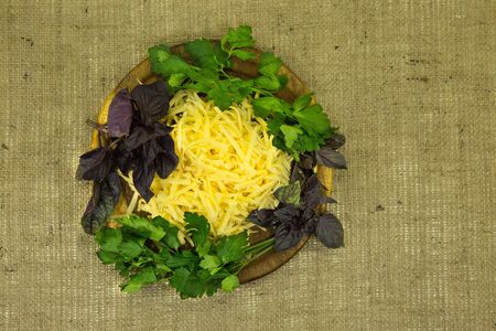 Good food. Grated cheese and fresh herbs. Stacked on a wooden kitchen end against the background of...