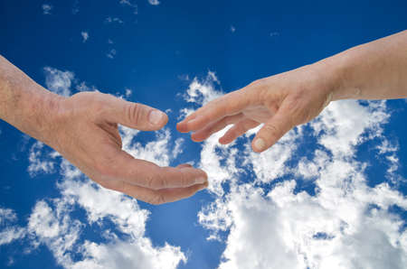 Moments before the touch. Man's and woman's hands in front of clouds.