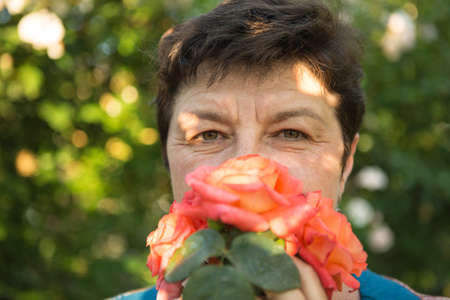 Picture of a middle-aged woman. Protection against coronavirus can also be beautiful. A woman has decorated the medical mask with roses.の写真素材
