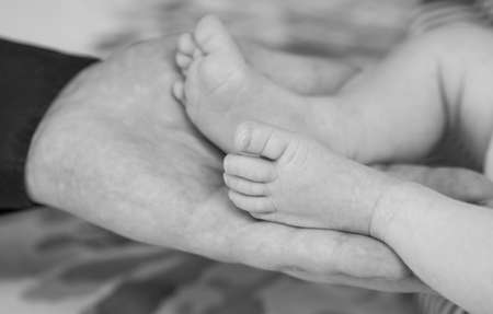 Children Babies. Child care. Small legs of a newborn baby in the hands of happy parentsの写真素材
