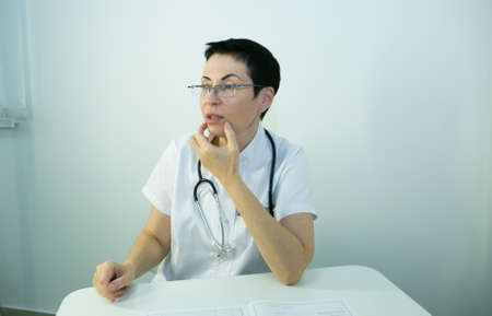 Doctor is a beautician. Portrait of a middle-aged woman. The doctor tells the patient about the need for facial skin care.の写真素材