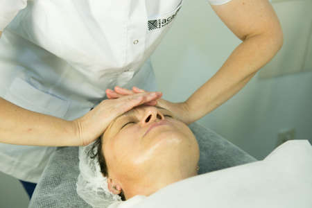 A visit to the beautician. Procedure-carboxytherapy. Doctor cosmetologist makes facial massage of the patient after the procedure.の写真素材