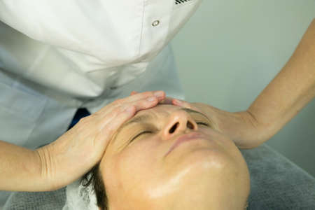 A visit to the beautician. Procedure-carboxytherapy. Doctor cosmetologist makes facial massage of the patient after the procedure.の写真素材