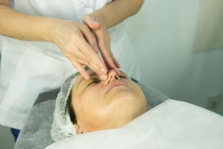 A visit to the beautician. Procedure-carboxytherapy. Doctor cosmetologist makes facial massage of the patient after the procedure.の写真素材