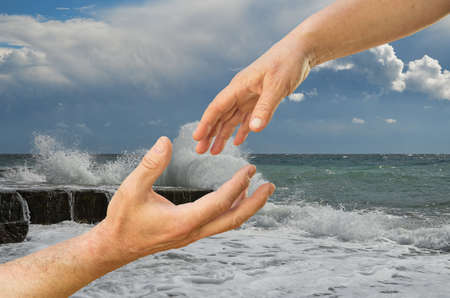 Moments before the touch. Man's and woman's hands in front of sea.