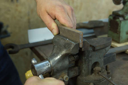 Working with a vise and drill. Master's hands at work. Home workshop.