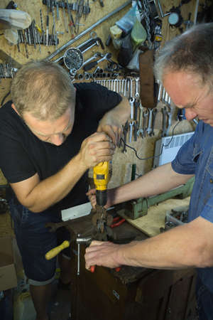 Working with a vise and drill. The master uses a drill. Portrait of a master at work. The young man...