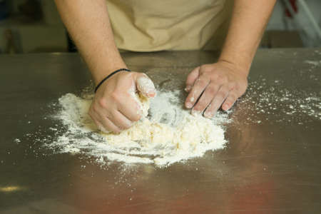 The production process for sweet pastries with fruits. The chef makes the baking dough by hand. The man adds and mixes the ingredients.の写真素材