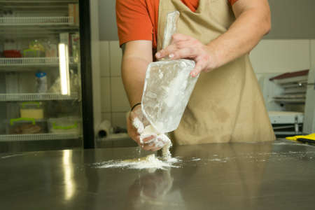 The production process for sweet pastries with fruits. The chef makes the baking dough by hand. The man adds and mixes the ingredients.の写真素材