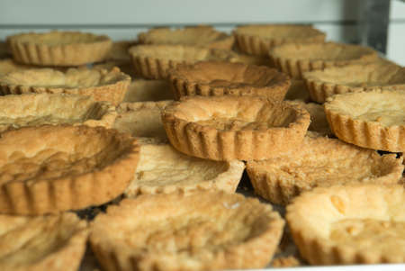 The production process for sweet pastries with fruits. Freshly baked tartlets. Prepared for cream...