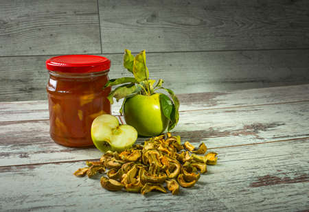 Still life. Close up of fruit jam and fresh yellow apples on an old rustic wooden table. Autumn...