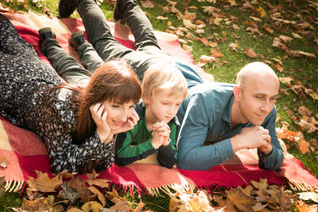 Fall. Happy family - mom, dad and son during a walk in the autumn park. Emotion concept. The boy and his parents are in a good mood.の写真素材