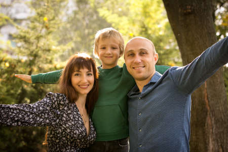 Fall. Happy family - mom, dad and son during a walk in the autumn park. Emotion concept. The boy and...