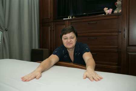 Homework. A middle-aged woman covers fresh bedding.