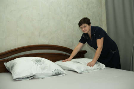 Homework. A middle-aged woman covers fresh bedding.