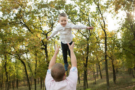 Fall. Close-up of happy and laughing dad and son on the background of the autumn forest.