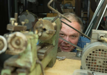 Humor. A middle-aged man fooling around in a friend's home workshop.