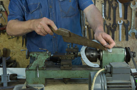 Humor. A middle-aged man fooling around in a friend's home workshop. Clos-up men hands and tool.
