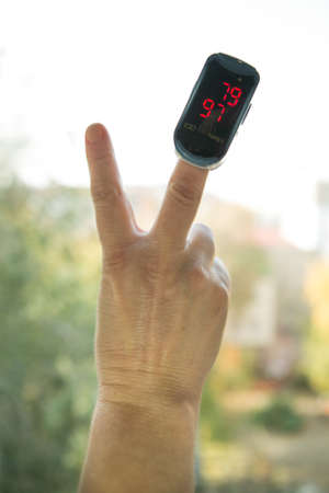 Blood oxygen saturation is the most important indicator of health status in the context of the coronavirus pandemic. Human hand with a pulse oximeter on the finger. Hand gestures.の写真素材