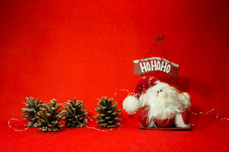 New Year and Christmas card on a red background. Spruce cones and cheerful Santa Claus. Content for the designer.の写真素材
