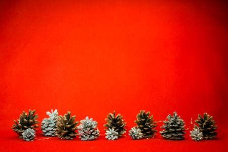 New Year and Christmas card on a red background. Spruce silver and natural cones with Christmas garlands. Content for the designer.の写真素材