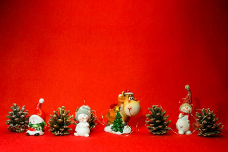New Year and Christmas card on a red background. Piggy bank in the shape of a cow wearing a santa...