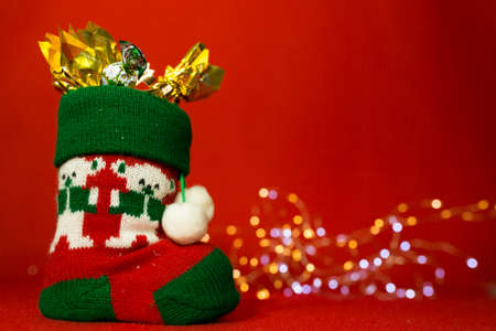 New Year and Christmas card on a red background. Boot with sweets and Christmas lights. Content for St. Nicholas Day.の写真素材
