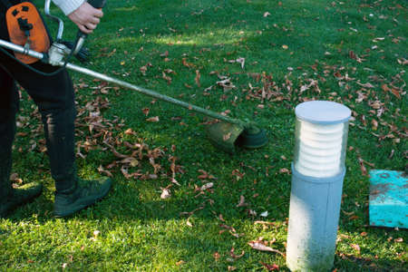 Autumn work in the park. The gardener cuts the grass before winter.