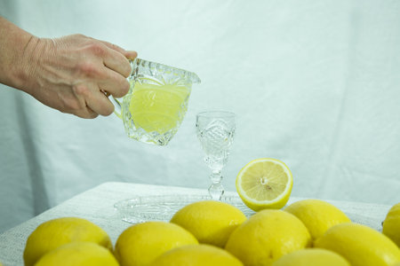 Limoncello. Female hand pouring a drink into a glass. Traditional homemade lemon liqueur limoncello...