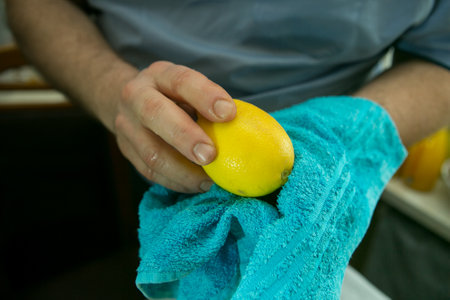 The process of making limoncello lemon liqueur at home. A man wipe washed lemons with a dry clean napkin.の写真素材