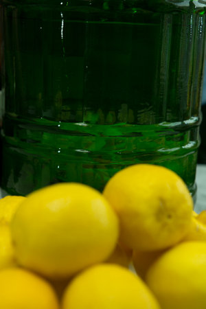 The process of making limoncello lemon liqueur at home. Fresh washed lemons on the background of a container with alcohol.の写真素材