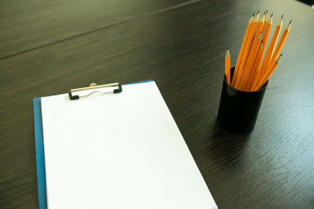 Pencils in a black plastic pencil case and a blank white notepad on a wooden table. Learning concept.の写真素材